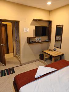 a room with a bed and a tv and a table at Hotel Heavens in Dum-Dum Junction