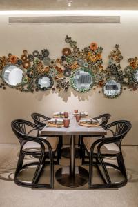 a table with chairs in front of a wall at Amaaranth Goa in Varca