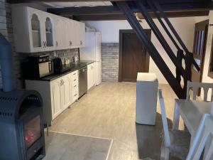 a kitchen with white cabinets and a stove at Chalupa Lipka in Kolárovice +4 photos