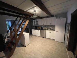 a kitchen with white cabinets and a staircase in a room at Chalupa Lipka in Kolárovice