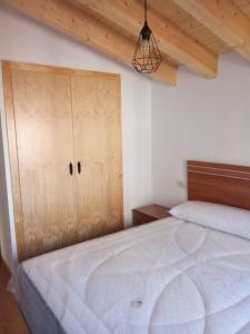 a bedroom with a large bed and a wooden cabinet at Casa Abuela Antolina in La Horcajada