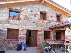 a brick house with a table and a balcony at Casa Abuela Antolina in La Horcajada
