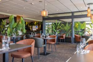 a restaurant with tables and chairs and plants at Fletcher Hotel-Restaurant Paasberg in Lochem