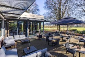 a patio with tables and chairs and umbrellas at Fletcher Hotel-Restaurant Paasberg in Lochem