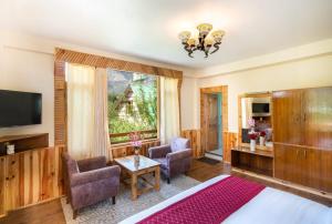 a bedroom with a bed and chairs and a television at Manali Golden Valley in Manāli