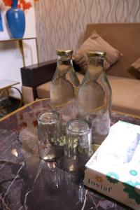three glass bottles and glasses sitting on a table at Sundown Resort in Noida