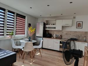 a kitchen with white cabinets and a table and chairs at SAS Militaria dla 2 par 2 pokoje 4 osobysamodzielne zameldowanie, kody w wiadomości przed przyjazdem in Borne Sulinowo