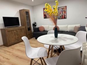 a living room with a table with a vase with yellow flowers at SAS Militaria dla 2 par 2 pokoje 4 osobysamodzielne zameldowanie, kody w wiadomości przed przyjazdem in Borne Sulinowo