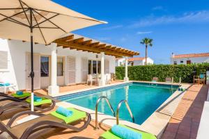 a villa with a swimming pool with chairs and an umbrella at Villa Las Rosas by Villa Plus in S'Algar