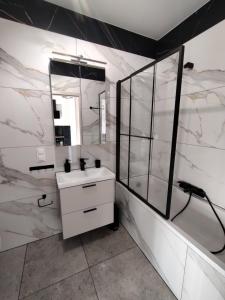 a white bathroom with a sink and a shower at Nowoczesny Apartament 400 M Od Plaży Prywatny Ogródek Ełk in Ełk