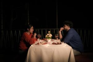 a man and woman sitting at a table with a plate of food at Kashmeeram Vythiri Wayanad Premium Pool Resort in Vayittiri