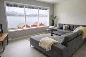 a living room with a couch and a large window at Senja Sjøtun House in Senja +5 photos