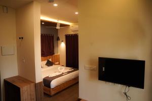 a bedroom with a bed and a flat screen tv at Kashmeeram Vythiri Wayanad Premium Pool Resort in Vayittiri
