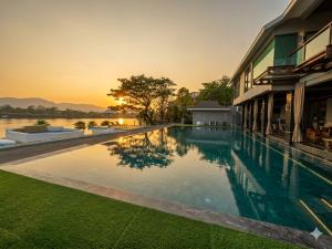 a swimming pool in front of a building with a sunset at The Lakeside Sanctuary in Ban Mae Cho