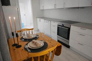 a kitchen with a wooden table with plates and candles at Senja Sjøtun House in Senja