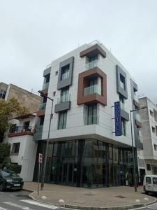 a building on a street with cars parked in front of it at Agdotel Urban Suites in Rabat