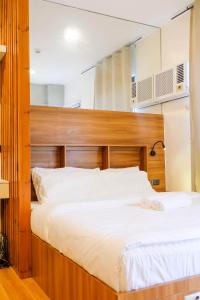 a bedroom with a large bed with a wooden headboard at Chill Studio w Balcony & Free Pool Lapu-Lapu in Mactan Island +22 photos