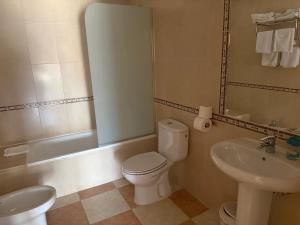 a bathroom with a white toilet and a sink at Hostal Cabañas in Carboneras de Guadazaón