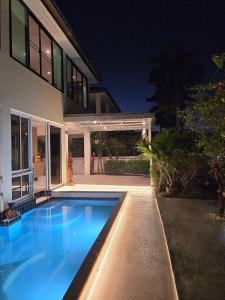 a swimming pool in front of a house at night at Pool Villa 25 in Ban Nong Pru