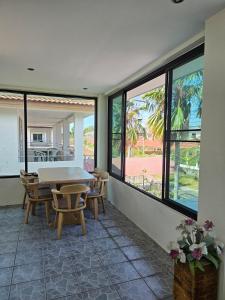 a dining room with a table and chairs and windows at Pool Villa 25 in Ban Nong Pru