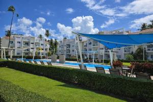 a row of chairs next to a swimming pool with buildings at Sol Tropical apartamentos in Punta Cana