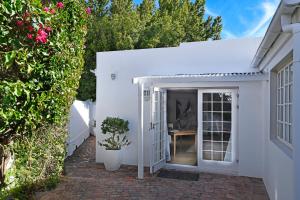 a white house with a door and a table at Mirabelle Guesthouse in Franschhoek