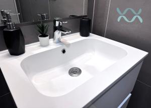 a white sink in a bathroom with a mirror at Római Ház Apartman in Siófok +15 photos