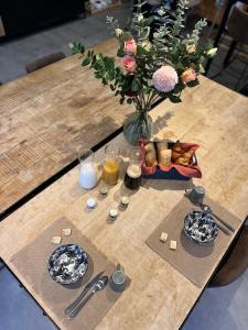 a wooden table with a vase of flowers and food on it at Suite La Clé de la Liberté Maison Like and Love 25m2 avec coin salon in Duclair
