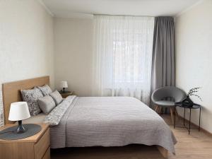 a bedroom with a bed and a chair and a window at Imantas apartment in Daugavpils