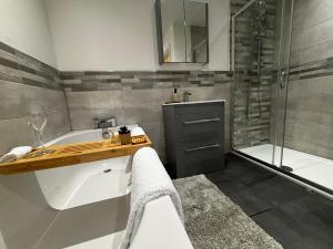 a bathroom with a tub and a sink and a shower at Holdsworth House Apartments in Killingbeck +22 photos