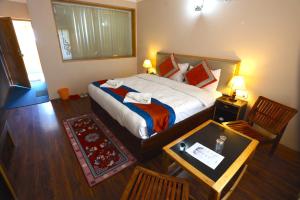 a bedroom with a bed and a table and a chair at Hotel Latso Ladakh in Leh