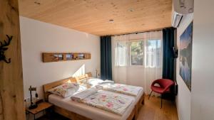 a bedroom with a bed and a red chair at Ferienhaus Haus im Garten in Feldkirch