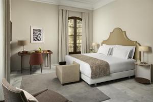 a bedroom with a large white bed and a desk at NH Collection Palacio de Córdoba in Córdoba