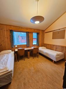 a room with two beds and a table and chairs at Alta Folkehøgskole in Alta