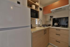 a kitchen with a white refrigerator and wooden cabinets at Vertacoflav - Bungalow - 6 couchages in Carry-le-Rouet