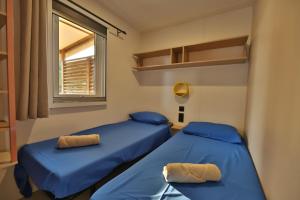 two blue beds in a room with a window at Vertacoflav - Bungalow - 6 couchages in Carry-le-Rouet +11 photos
