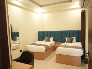 a hotel room with two beds and a mirror at The RaaS Guestline in Noida