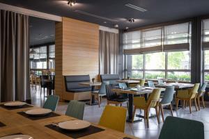 a dining room with tables and chairs and windows at Nobel Inn Hotel in Belgrade