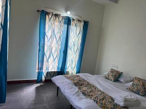 a bedroom with two beds and a window with blue curtains at The Redstones Resort in Malvan