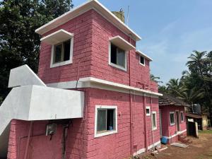 a pink house with white windows on the side of it at The Redstones Resort in Malvan