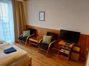 a hotel room with two chairs and a television at Penzion U Kuboňů in Volary