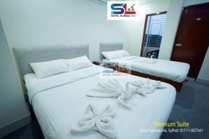 two beds in a hotel room with bows on them at Hotel SurmaLink in Sylhet