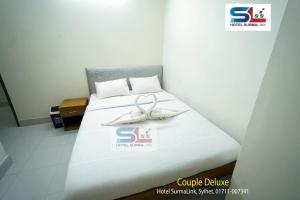 a bed with two white shoes on top of it at Hotel SurmaLink in Sylhet