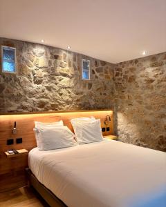 a bedroom with a large bed and a stone wall at Hotel B Lodge in Saint-Tropez