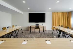 a conference room with tables and a large screen at Residence Inn by Marriott Lille in Lille