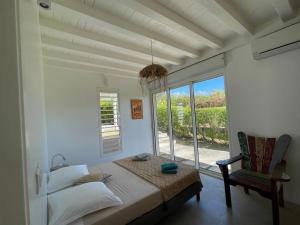 a bedroom with a bed and a chair and a window at Villa Ever Blue in Le Vauclin