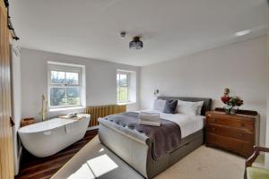 a bedroom with a large bed and a bathtub and a bath tub at Finest Retreats - Blackton Farmhouse in Barnard Castle
