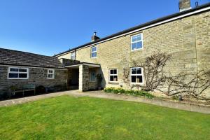 a brick house with a lawn in front of it at Finest Retreats - Blackton Farmhouse in Barnard Castle