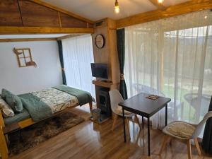 a bedroom with a bed and a table and a window at Cabana Mura in Olăneşti