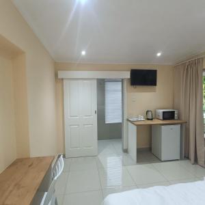 a room with a bed and a desk with a microwave at 75 on Albert Guesthouse in Gqeberha